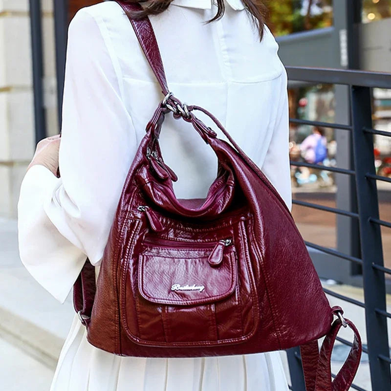 Vue de dos d’une femme en robe blanche portant un sac à main en cuir bordeaux de la marque Vanderwah.