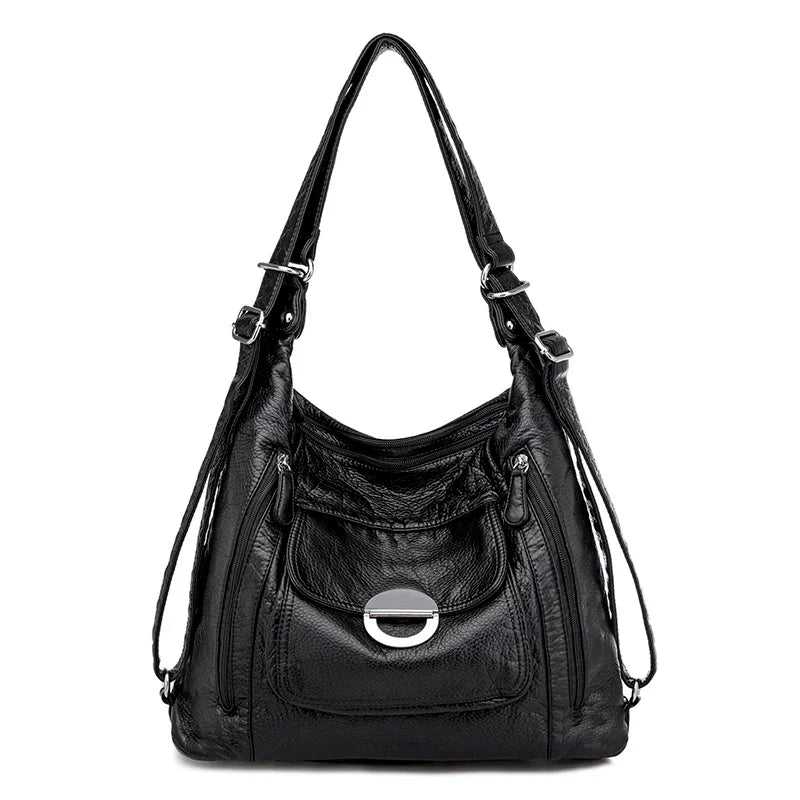 Sac à main en cuir noir de la marque Vanderwah, vu de face, avec une poche avant ornée d’une fermeture ronde métallique.