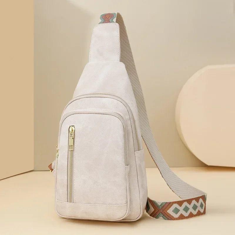 Sac à bandoulière beige clair en cuir PU, avec sangle ethnique multicolore, présenté dans un décor doux aux tons sable pour une ambiance naturelle.