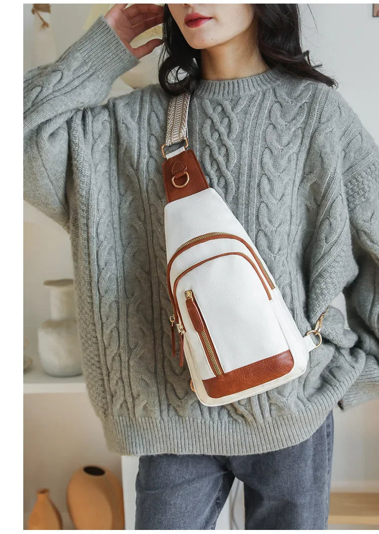 Femme portant un sac à bandoulière blanc et marron en cuir PU, en travers du corps sur un pull en maille torsadée gris, style casual et chaleureux.