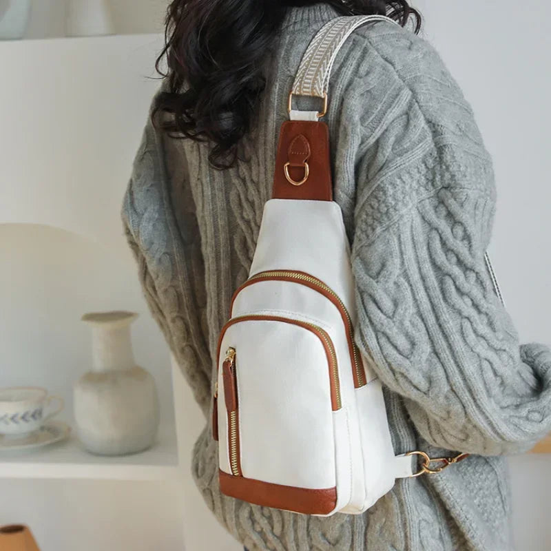 Vue de dos d’une femme portant un sac à bandoulière blanc et marron, avec un pull en maille torsadée gris, dans un intérieur minimaliste.