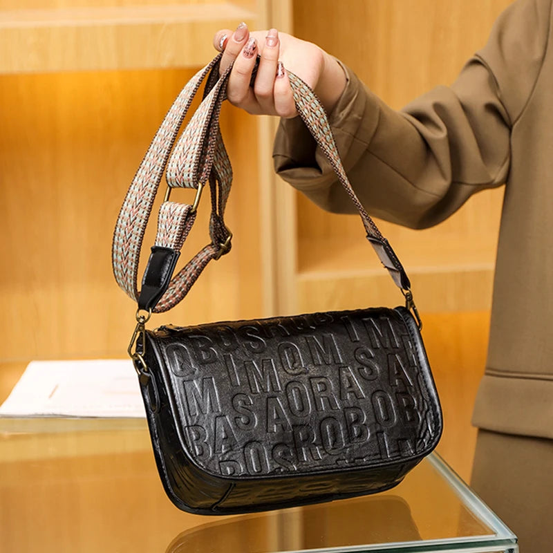 Sac à bandoulière vintage pour femme en cuir embossé noir, avec sangle tressée beige et rouge.