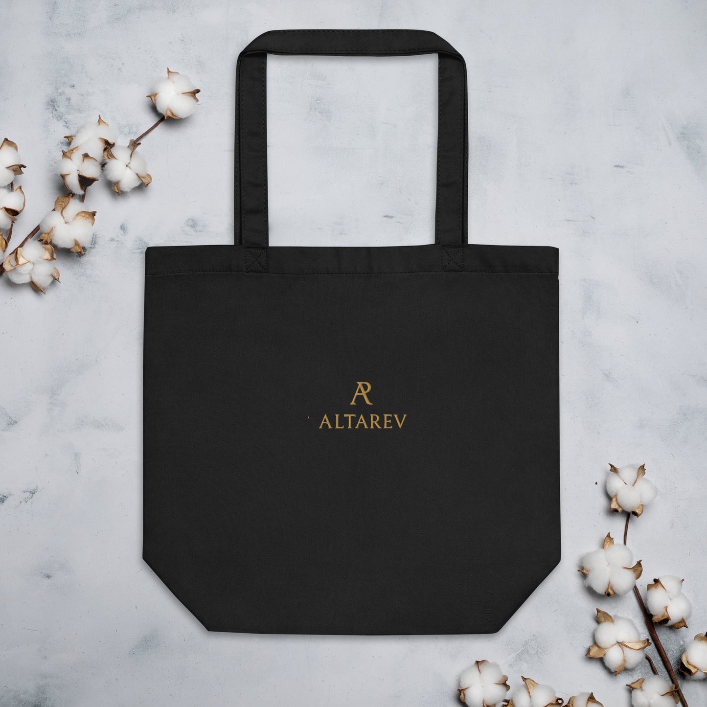 Sac ALTAREV noir – logo doré, à plat sur fond minimaliste avec fleurs de coton