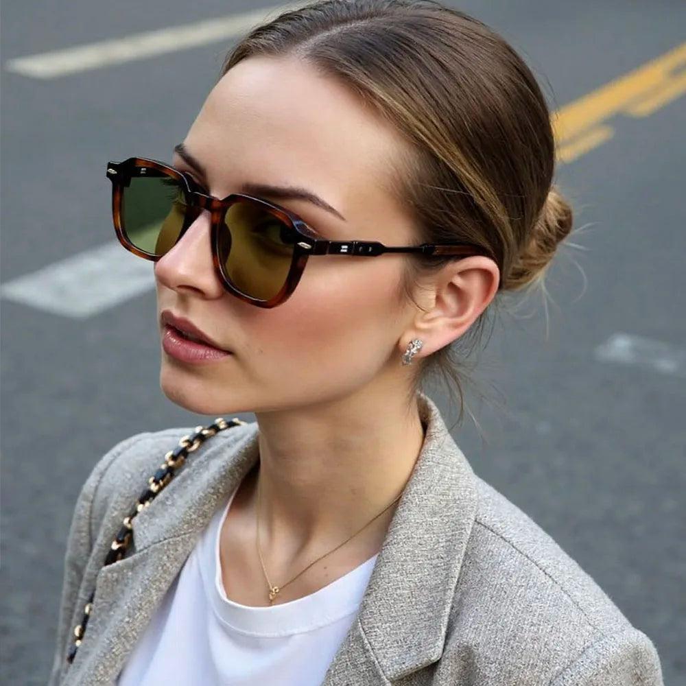 Femme élégante portant des lunettes de soleil vintage ALTAREV – monture écaille, look chic en extérieur urbain.