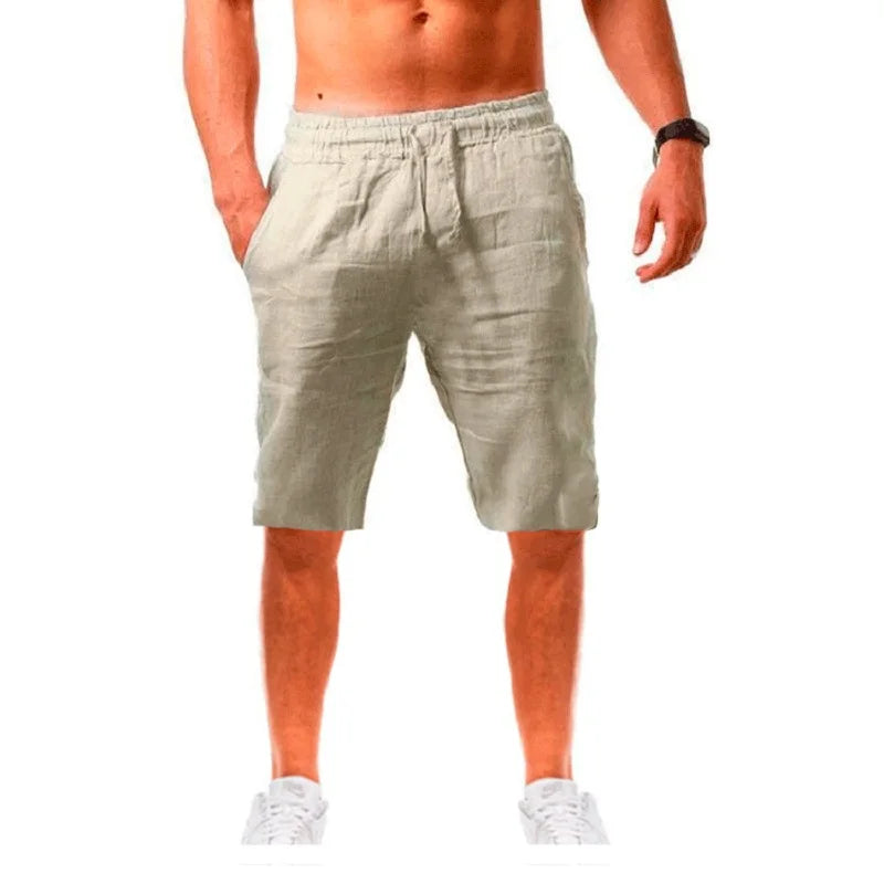 Homme élégant portant un short beige en lin ALTAREV, marchant près de la mer sur des escaliers blancs, ambiance estivale chic.