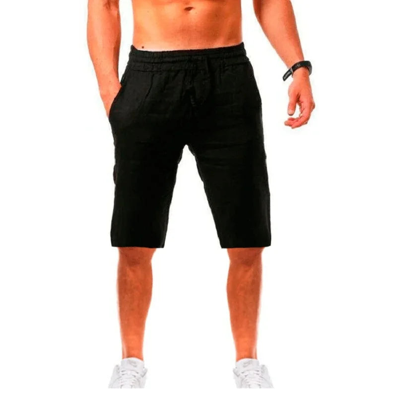 Homme élégant portant un short noir en lin ALTAREV, marchant près de la mer sur des escaliers blancs, ambiance estivale chic.