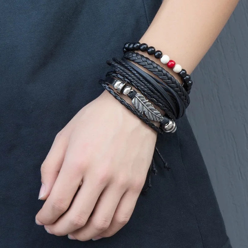 Bracelet homme multirang en cuir noir avec perles naturelles noires, rouges et blanches, orné d’une plume argentée, porté au poignet.
