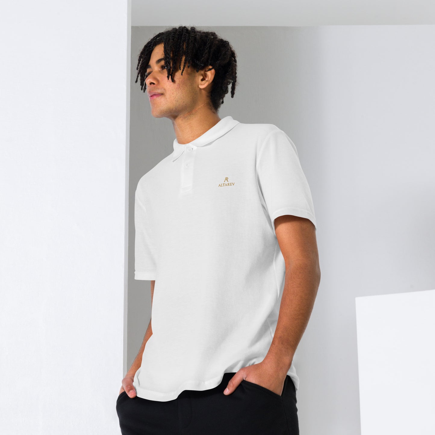 Homme portant un polo ALTAREV blanc brodé or, posé en studio, style minimaliste et premium.
