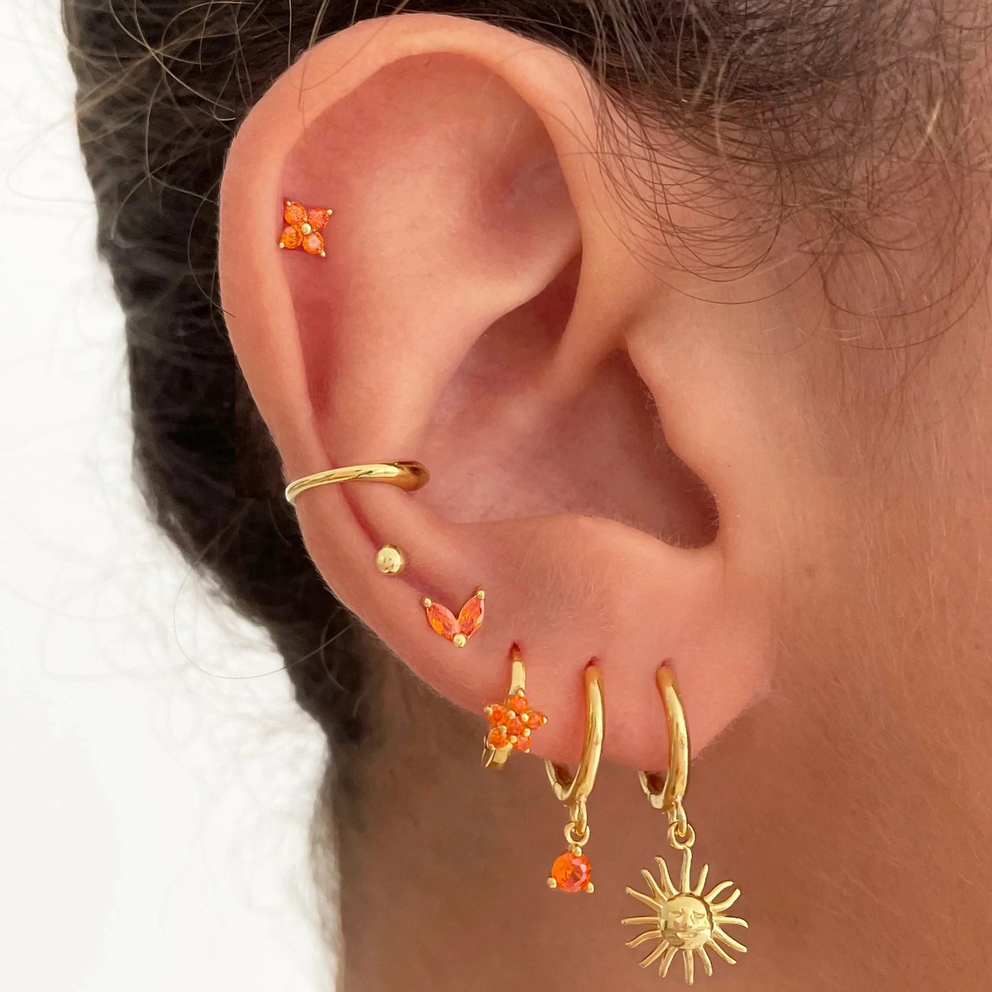 Boucles d’oreilles créoles dorées 18K portées, avec pendentifs solaires