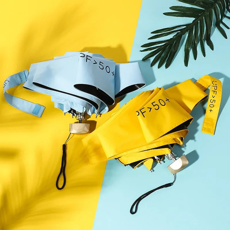 Parapluies pliables jaune vif et bleu ciel avec protection UV UPF50+, posés sur fond bicolore tropical.
