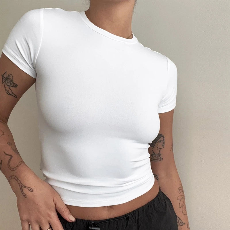 T-shirt blanc moulant pour femme – coupe slim, col rond, manches courtes, porté avec un pantalon noir, style moderne et épuré.
